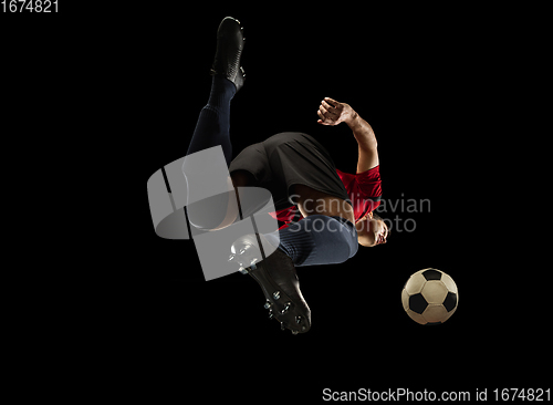 Image of Young caucasian football, soccer player in action, motion isolated on black background, look from the bottom. Concept of sport, movement, energy and dynamic.