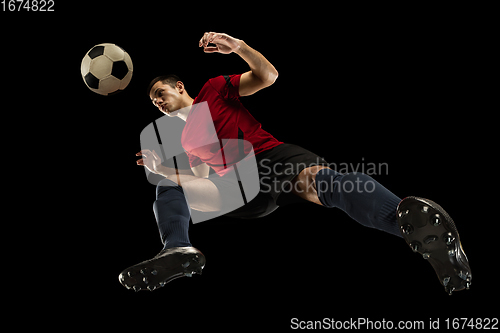 Image of Young caucasian football, soccer player in action, motion isolated on black background, look from the bottom. Concept of sport, movement, energy and dynamic.