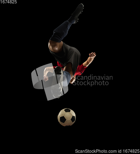 Image of Young caucasian football, soccer player in action, motion isolated on black background, look from the bottom. Concept of sport, movement, energy and dynamic.