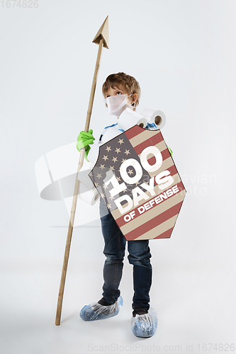 Image of Little caucasian boy as a warrior in fight with coronavirus pandemic, with a shield, a sword and a toilet paper bandoleer.