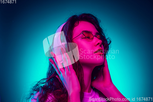 Image of Caucasian woman\'s portrait isolated on blue studio background in multicolored neon light