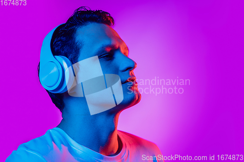 Image of Caucasian man\'s portrait isolated on purple blue studio background in multicolored neon light