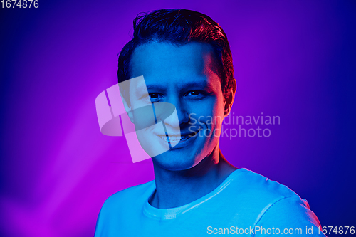 Image of Caucasian man\'s portrait isolated on purple blue studio background in multicolored neon light