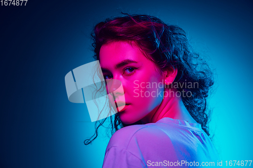 Image of Caucasian woman\'s portrait isolated on blue studio background in multicolored neon light