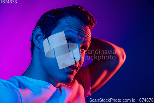 Image of Caucasian man\'s portrait isolated on purple blue studio background in multicolored neon light