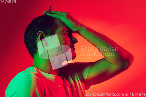 Image of Caucasian man\'s portrait isolated on red studio background in multicolored neon light