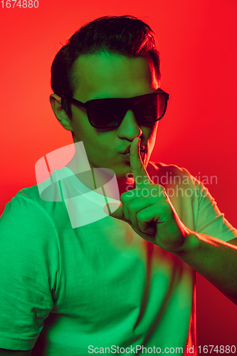 Image of Caucasian man\'s portrait isolated on red studio background in multicolored neon light