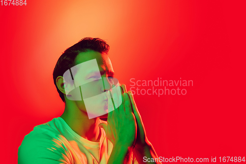 Image of Caucasian man\'s portrait isolated on red studio background in multicolored neon light