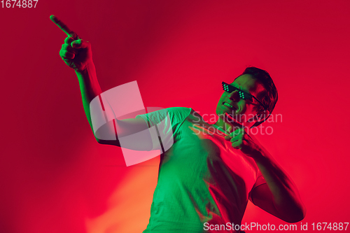 Image of Caucasian man\'s portrait isolated on red studio background in multicolored neon light
