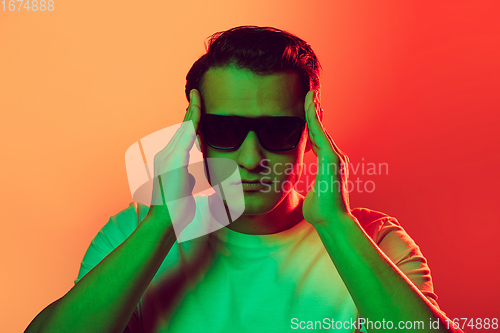 Image of Caucasian man\'s portrait isolated on red studio background in multicolored neon light