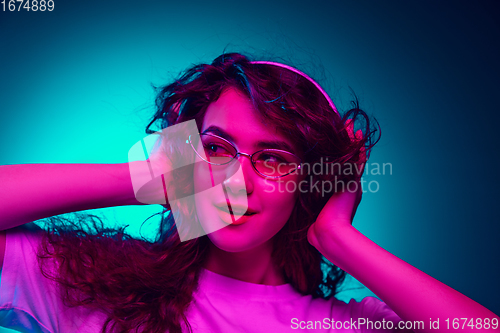 Image of Caucasian woman\'s portrait isolated on blue studio background in multicolored neon light