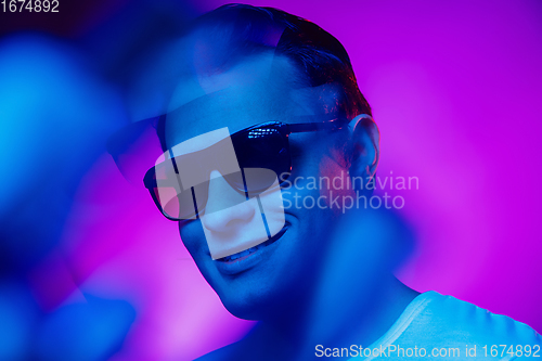 Image of Caucasian man\'s portrait isolated on purple blue studio background in multicolored neon light