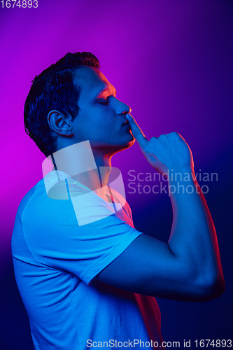 Image of Caucasian man\'s portrait isolated on purple blue studio background in multicolored neon light