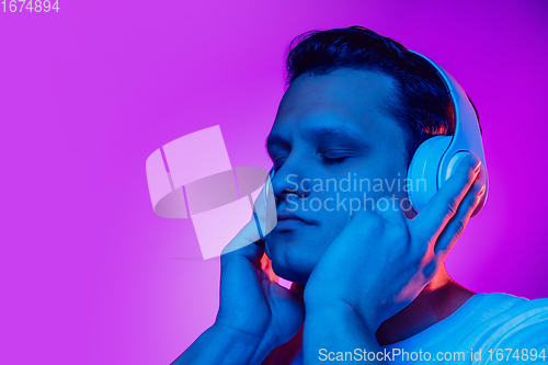 Image of Caucasian man\'s portrait isolated on purple blue studio background in multicolored neon light