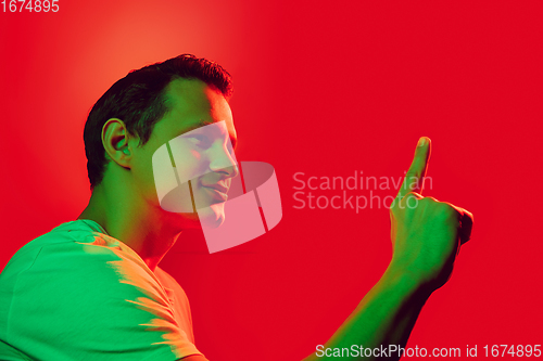 Image of Caucasian man\'s portrait isolated on red studio background in multicolored neon light