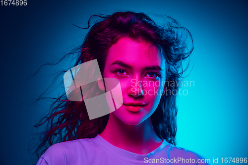 Image of Caucasian woman\'s portrait isolated on blue studio background in multicolored neon light