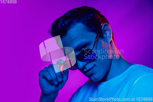 Image of Caucasian man\'s portrait isolated on purple blue studio background in multicolored neon light