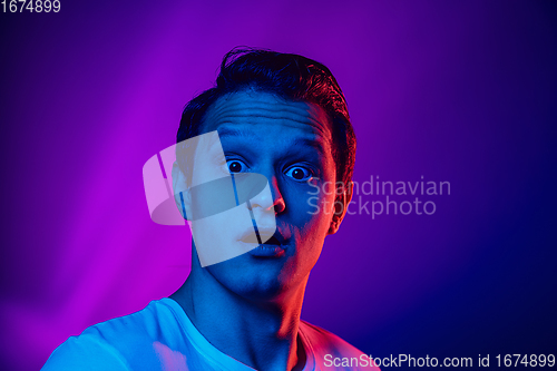 Image of Caucasian man\'s portrait isolated on purple blue studio background in multicolored neon light