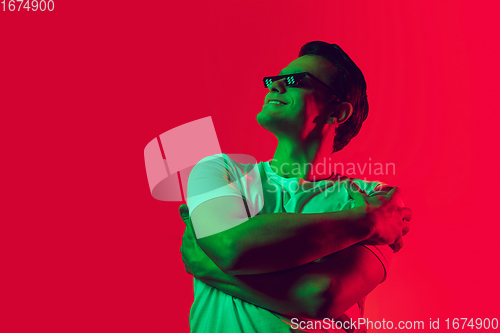 Image of Caucasian man\'s portrait isolated on red studio background in multicolored neon light