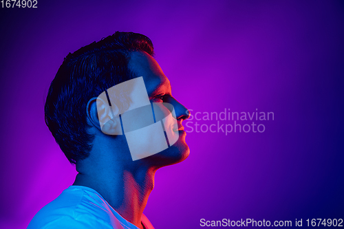 Image of Caucasian man\'s portrait isolated on purple blue studio background in multicolored neon light