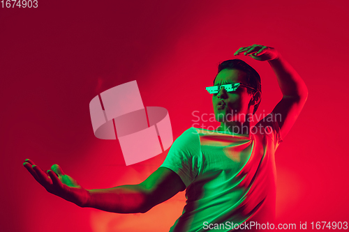 Image of Caucasian man\'s portrait isolated on red studio background in multicolored neon light