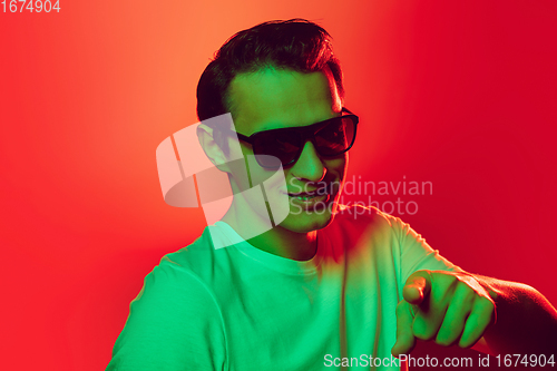 Image of Caucasian man\'s portrait isolated on red studio background in multicolored neon light