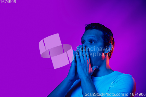 Image of Caucasian man\'s portrait isolated on purple blue studio background in multicolored neon light