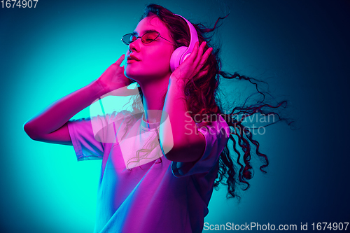 Image of Caucasian woman\'s portrait isolated on blue studio background in multicolored neon light