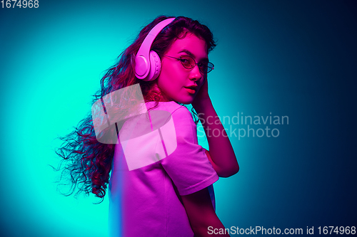 Image of Caucasian woman\'s portrait isolated on blue studio background in multicolored neon light