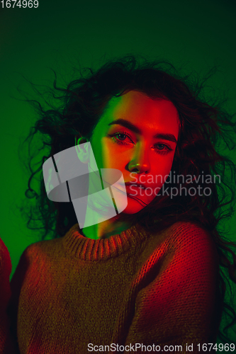 Image of Caucasian woman\'s portrait isolated on green studio background in multicolored neon light