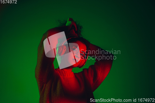 Image of Caucasian woman\'s portrait isolated on green studio background in multicolored neon light