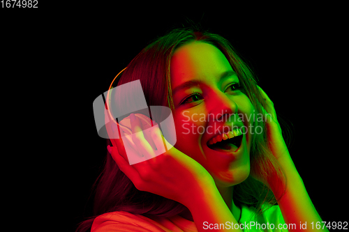 Image of Caucasian woman\'s portrait isolated on black studio background in multicolored neon light