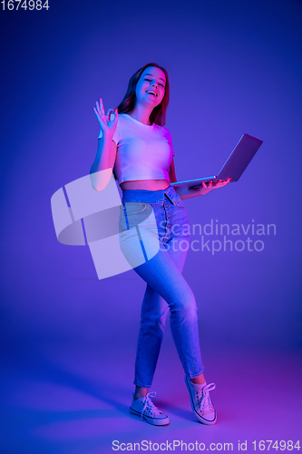 Image of Caucasian woman\'s portrait isolated on blue studio background in multicolored neon light