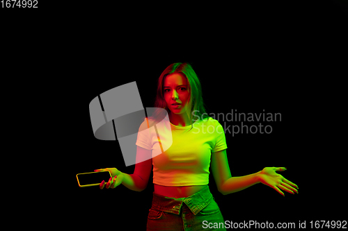 Image of Caucasian woman\'s portrait isolated on black studio background in multicolored neon light