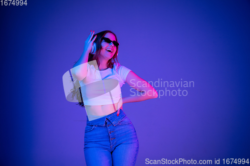 Image of Caucasian woman\'s portrait isolated on blue studio background in multicolored neon light