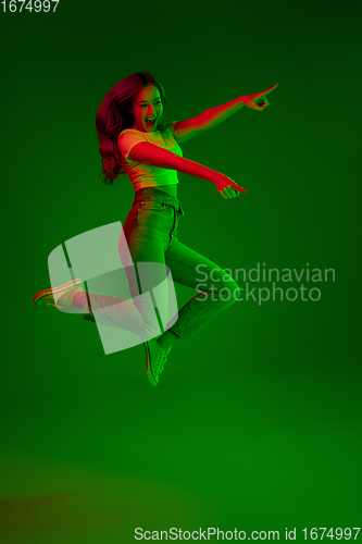 Image of Caucasian woman\'s portrait isolated on green studio background in multicolored neon light