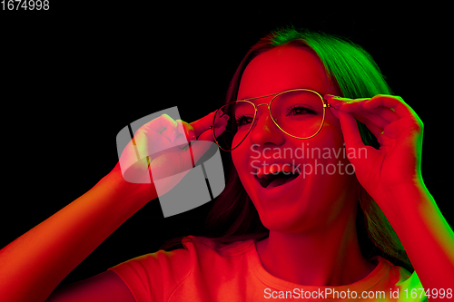 Image of Caucasian woman\'s portrait isolated on black studio background in multicolored neon light