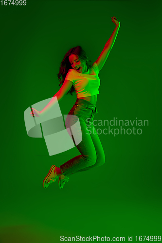 Image of Caucasian woman\'s portrait isolated on green studio background in multicolored neon light