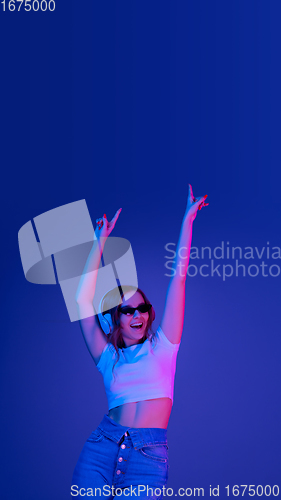 Image of Caucasian woman\'s portrait isolated on blue studio background in multicolored neon light