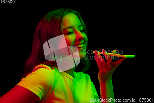 Image of Caucasian woman\'s portrait isolated on black studio background in multicolored neon light