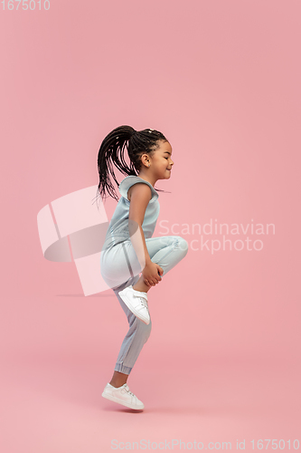 Image of Happy longhair brunette little girl isolated on pink studio background. Looks happy, cheerful, sincere. Copyspace. Childhood, education, emotions concept