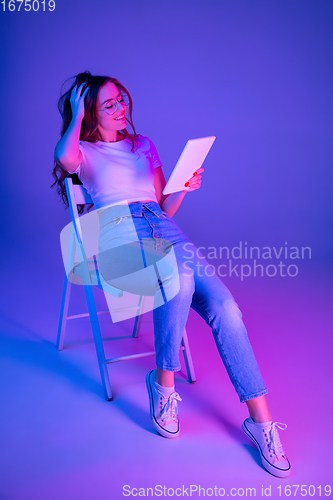 Image of Caucasian woman\'s portrait isolated on blue studio background in multicolored neon light