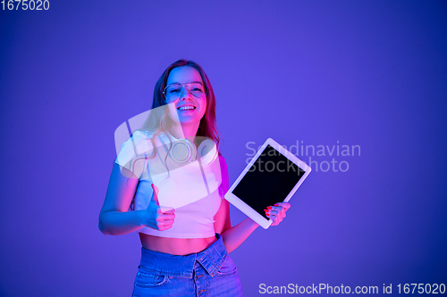 Image of Caucasian woman\'s portrait isolated on blue studio background in multicolored neon light