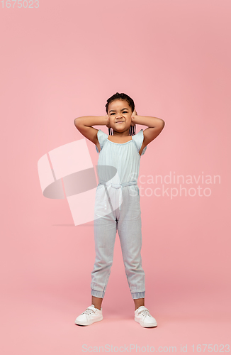 Image of Happy longhair brunette little girl isolated on pink studio background. Looks happy, cheerful, sincere. Copyspace. Childhood, education, emotions concept