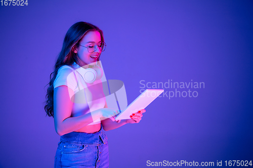 Image of Caucasian woman\'s portrait isolated on blue studio background in multicolored neon light