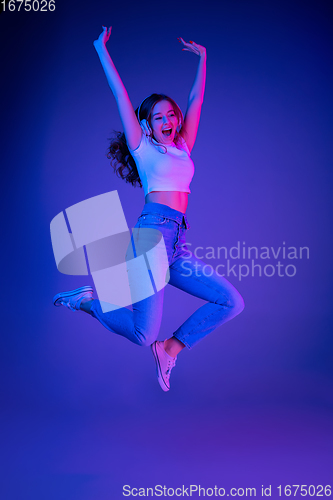 Image of Caucasian woman\'s portrait isolated on blue studio background in multicolored neon light