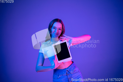 Image of Caucasian woman\'s portrait isolated on blue studio background in multicolored neon light