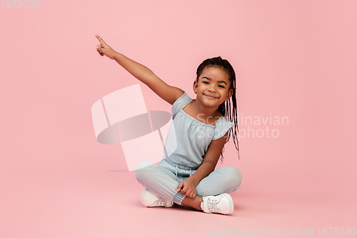 Image of Happy longhair brunette little girl isolated on pink studio background. Looks happy, cheerful, sincere. Copyspace. Childhood, education, emotions concept