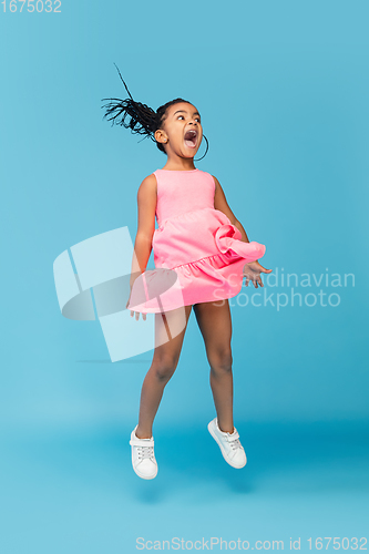 Image of Happy longhair brunette little girl isolated on blue studio background. Looks happy, cheerful, sincere. Copyspace. Childhood, education, emotions concept