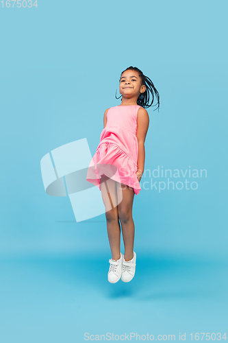 Image of Happy longhair brunette little girl isolated on blue studio background. Looks happy, cheerful, sincere. Copyspace. Childhood, education, emotions concept